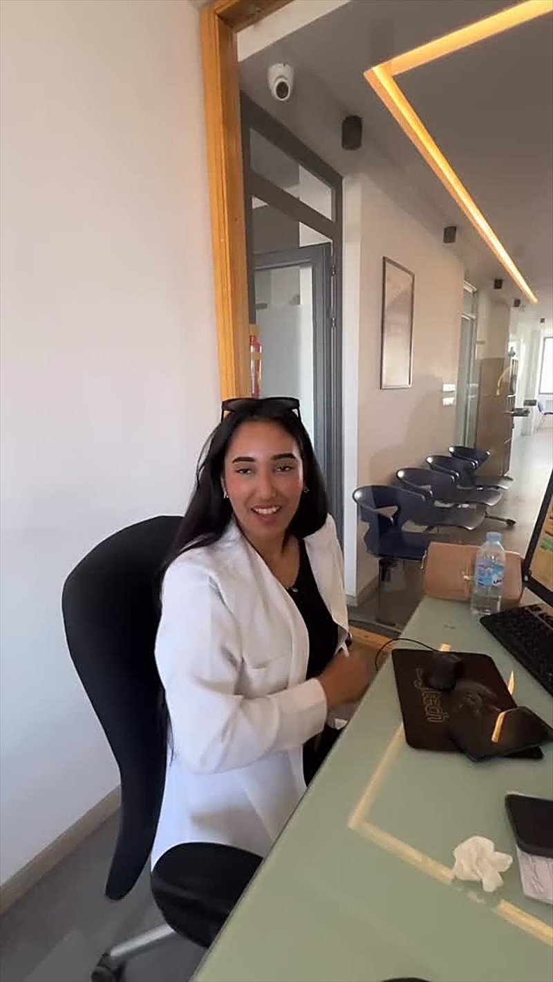Une étudiante souriante, assise à l’accueil du centre