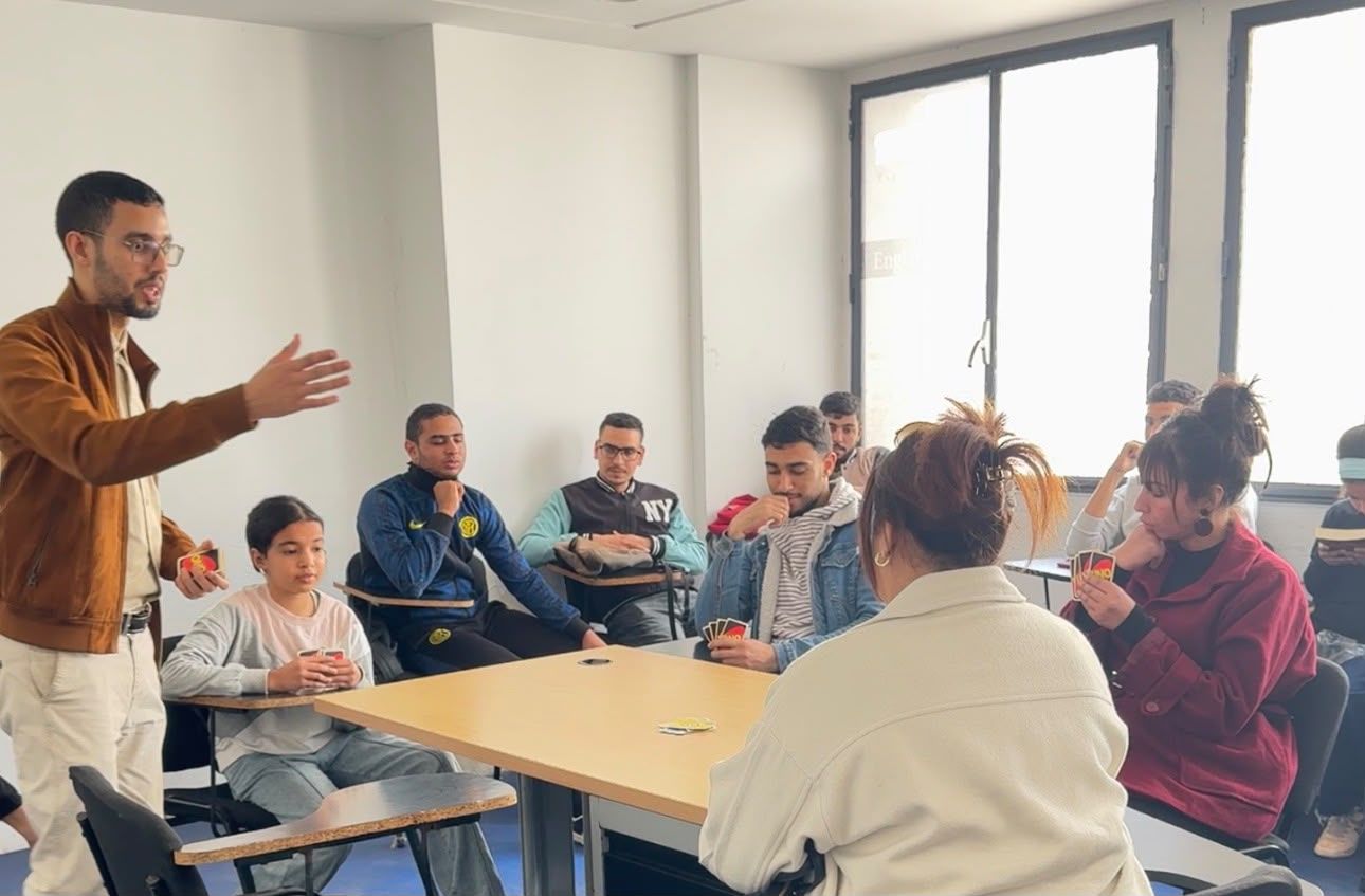 Un professeur anime un échange avec un groupe d’étudiants autour de la table